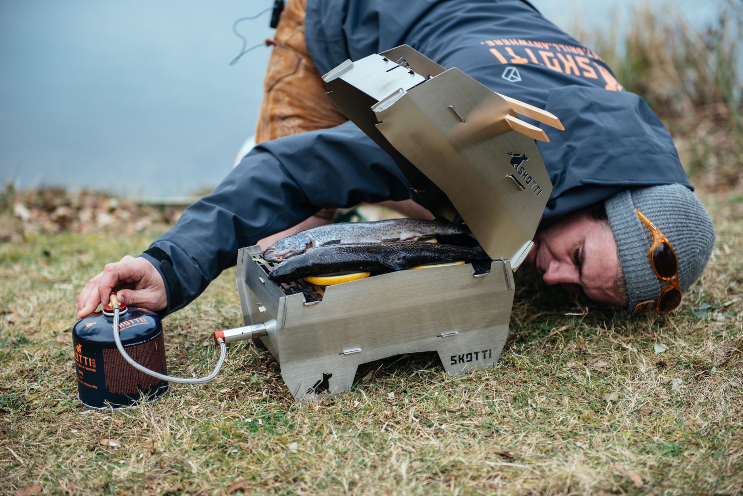 Junger Mann grillt im Freien Forelle auf dem SKOTTI Gasgrill